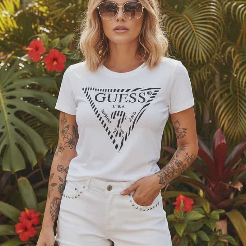 Модел със слънчеви очила, носещ бяла дамска тениска Guess с голямо черно лого триъгълник и бели къси панталони.