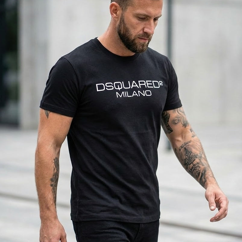 Мъж с черна тениска Dsquared2 Milano и татуировки на ръцете в градска среда