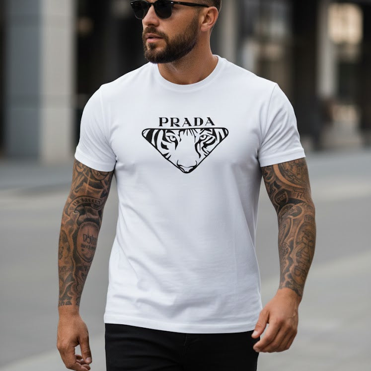 Мъж с татуировки и слънчеви очила, облечен в бяла тениска с логото на Prada и принт на тигър, в градска среда.