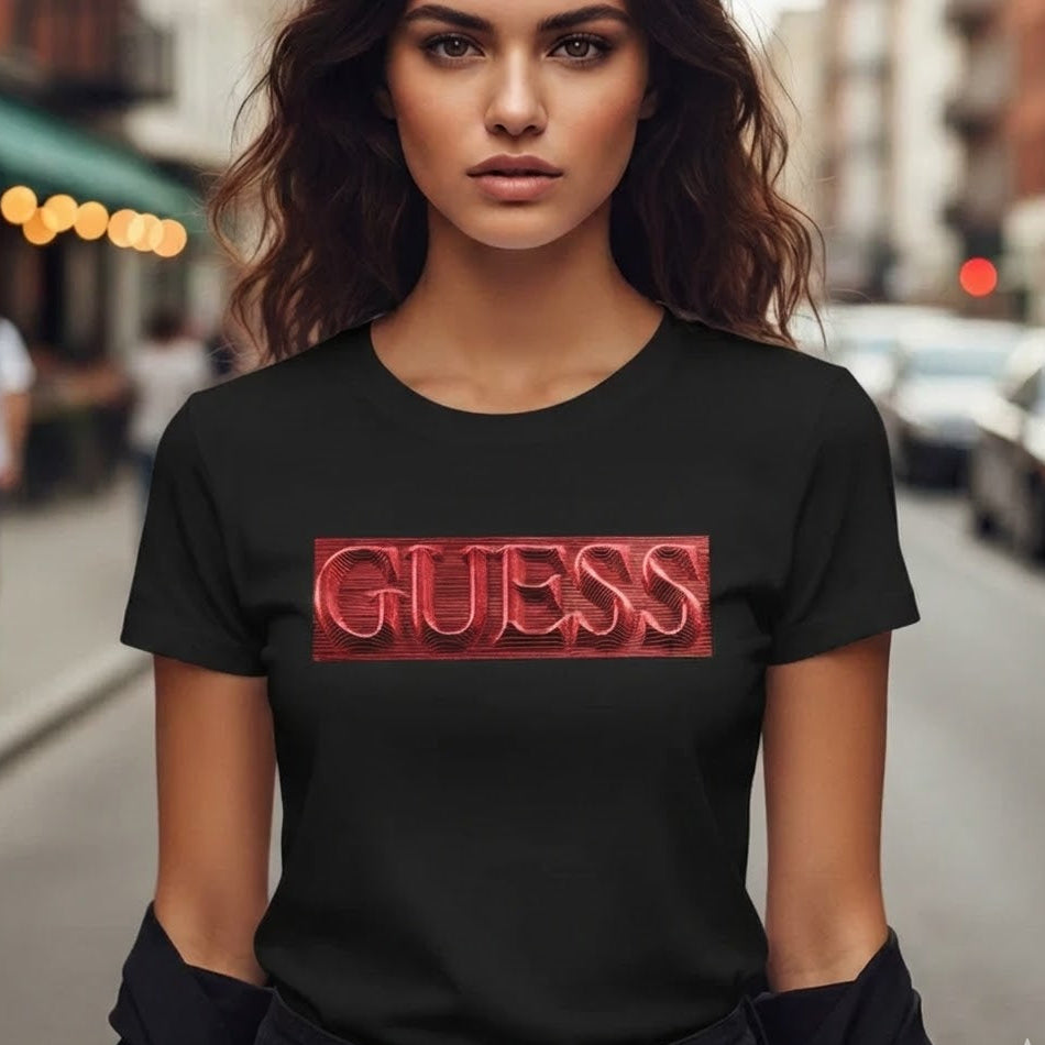 Дамска черна тениска GUESS с правоъгълно червено лого и вълнообразен 3D шрифт, носена от модел.