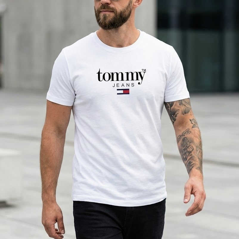 Мъж с брада и черни очила, облечен в бяла тениска Tommy Jeans с характерен черен надпис