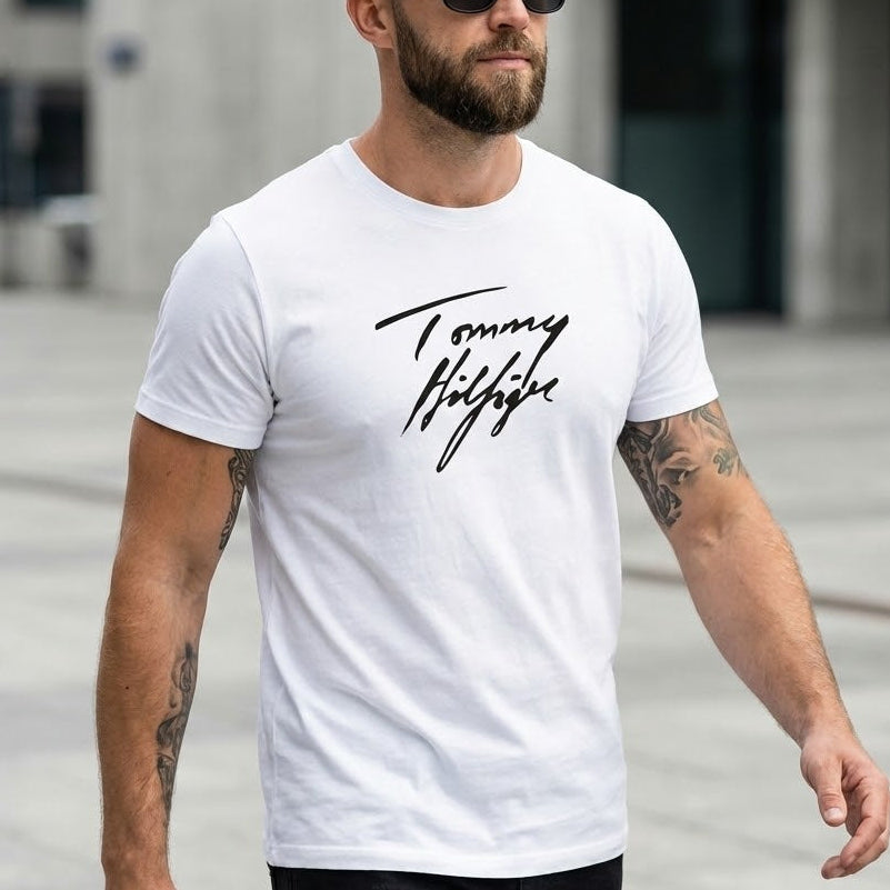 Мъж с бяла тениска Tommy Hilfiger с черен ръкописен надпис и татуировки