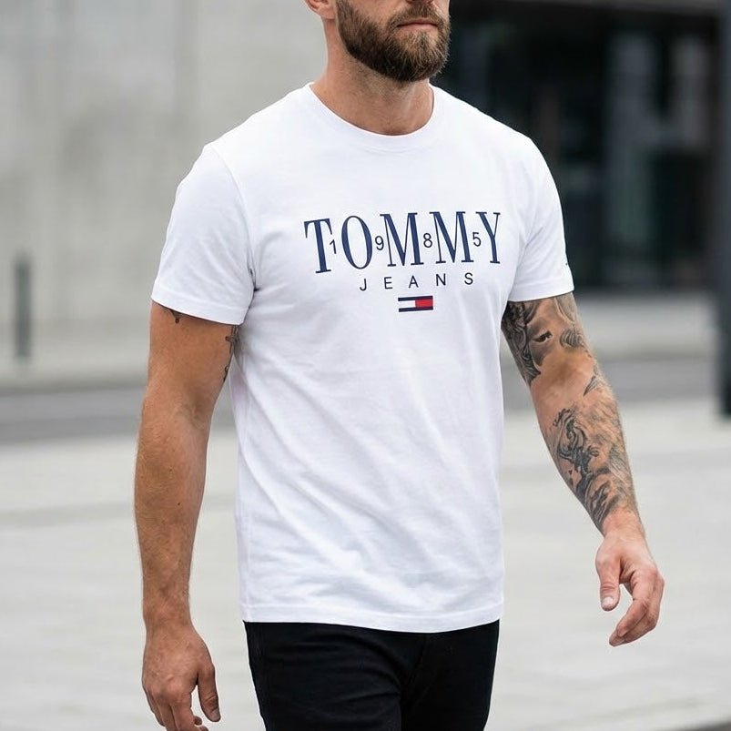 Мъж с бяла тениска Tommy Jeans с голям надпис и цветен флаг на гърдите