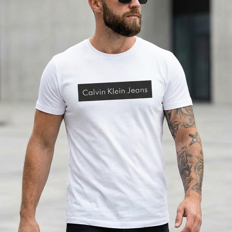 Мъж с бяла тениска Calvin Klein Jeans с изчистено черно правоъгълно лого на гърдите