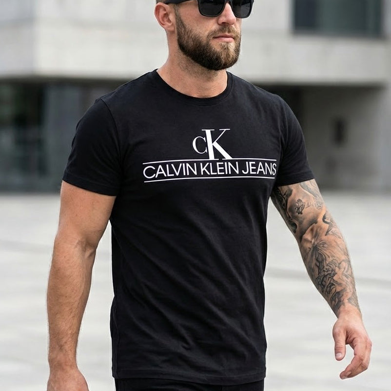 Мъж с черна тениска Calvin Klein Jeans с голямо бяло лого и монограм ck на гърдите