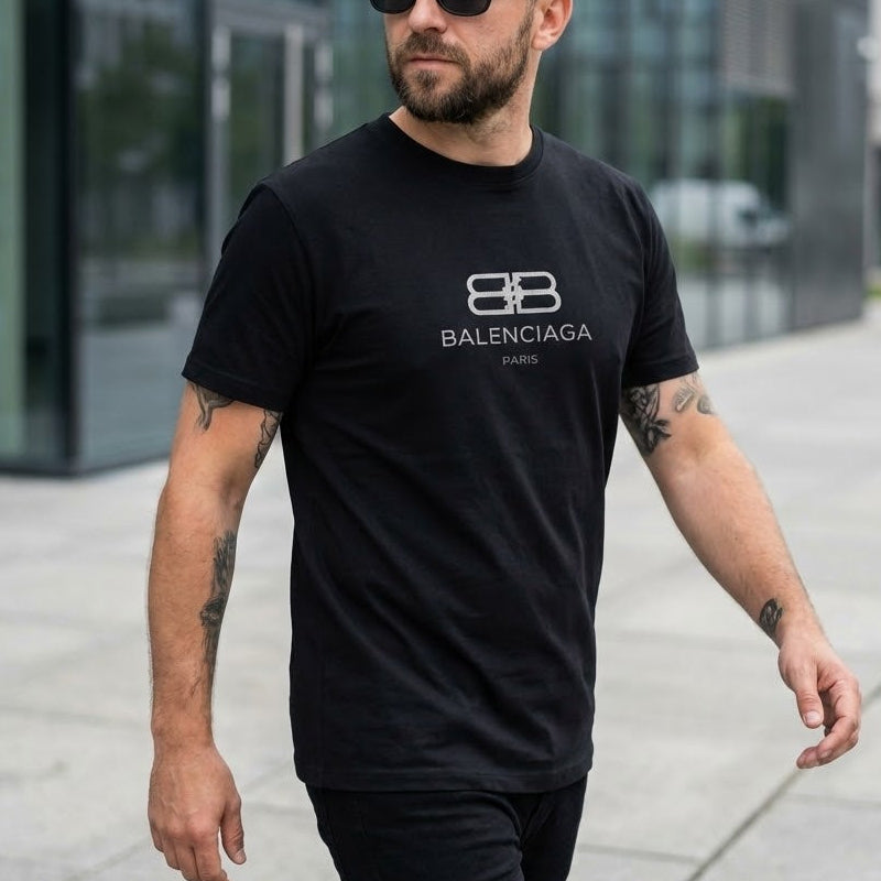 Мъж с черна тениска Balenciaga Paris със сребристо двойно "B" лого на гърдите